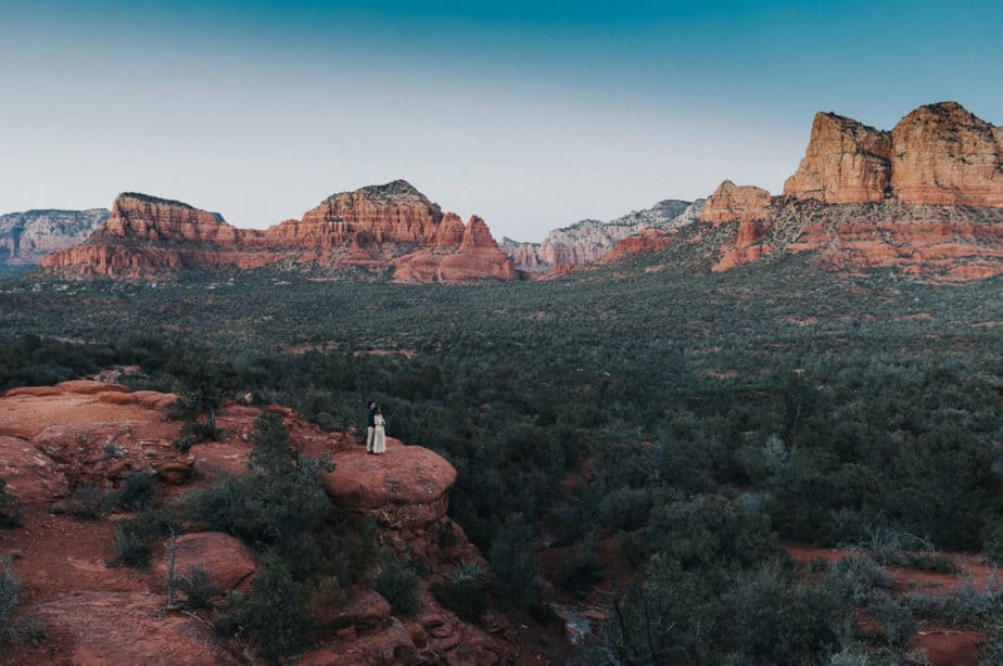 Bride and groom on the edge of a cliff in Sedona, Arizona.