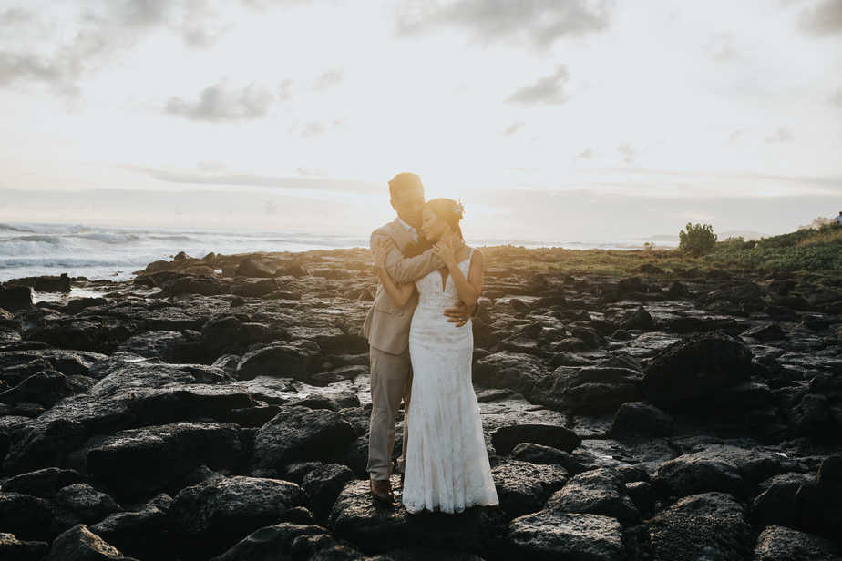 Bride and groom pose on the beach in Kauai, Hawaii.