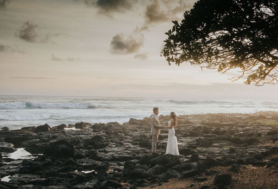 Groom and bride pose on the beaches next to their reception in Kauai, Hawaii.