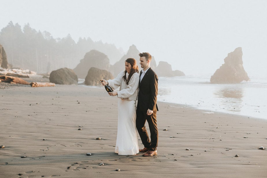 Bride and groom pop champagne at Second Beach during their elopement in La Push, Washingon.