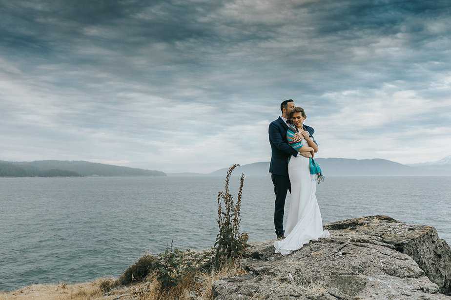 Bride and groom embrace on a cliff in Port angeles, WA