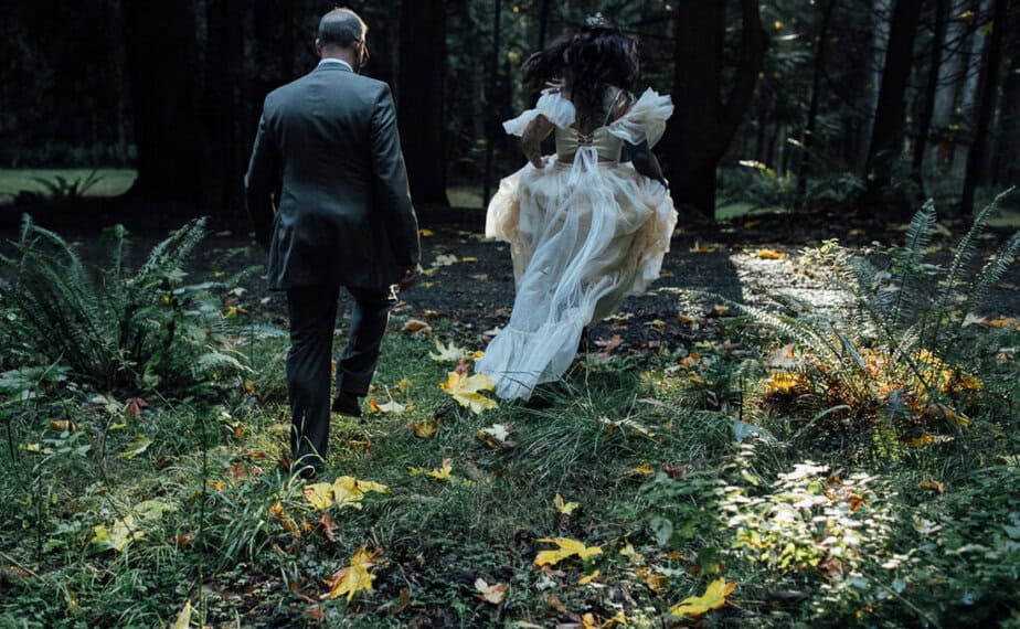 Bride and groom running through the woods on their elopement day.