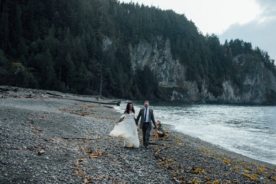 Bride and groom stroll along the ocean in Olympic National Park.