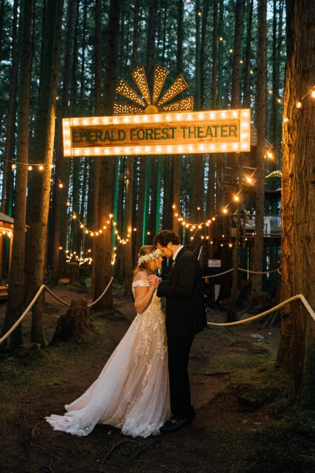 Bride and groom pose under a sign at Emerald Forest Theatre in Redmond, Washington.