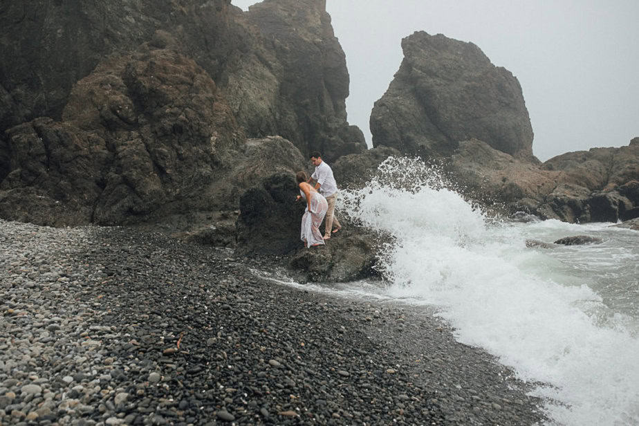 Bride and groom run away from the waves at Ruby Beach in Olympic National Park.