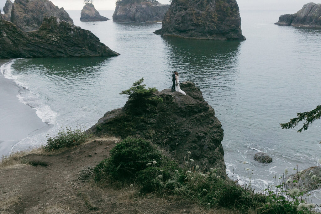 Bride and groom pose for portraits in the rain in Brookings, Oregon.