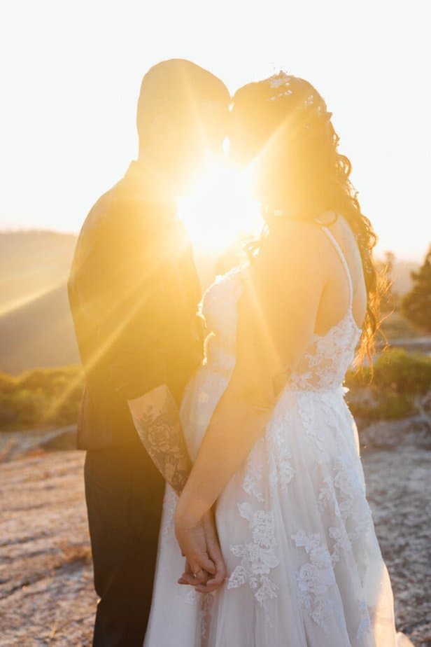 The sun peeks through a couple eloping during the elopement in California. 