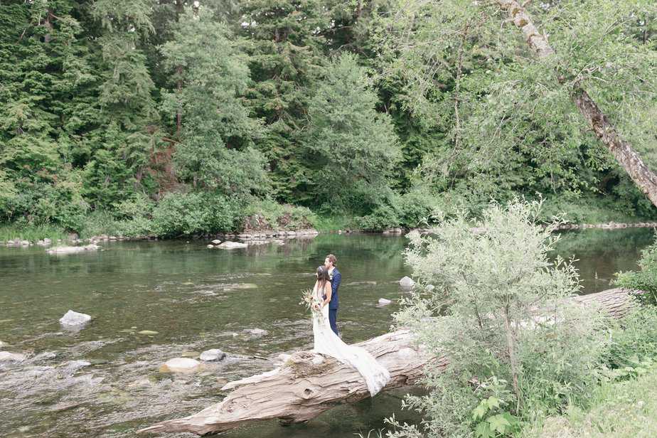 Bride and groom pose for pictures along the Hoh River in Forks, Washington.