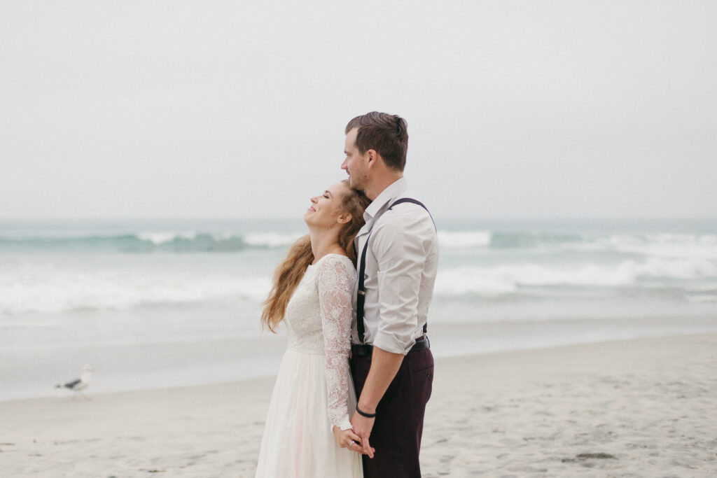 Bride and groom laugh together on the beaches of La Jolla, California.