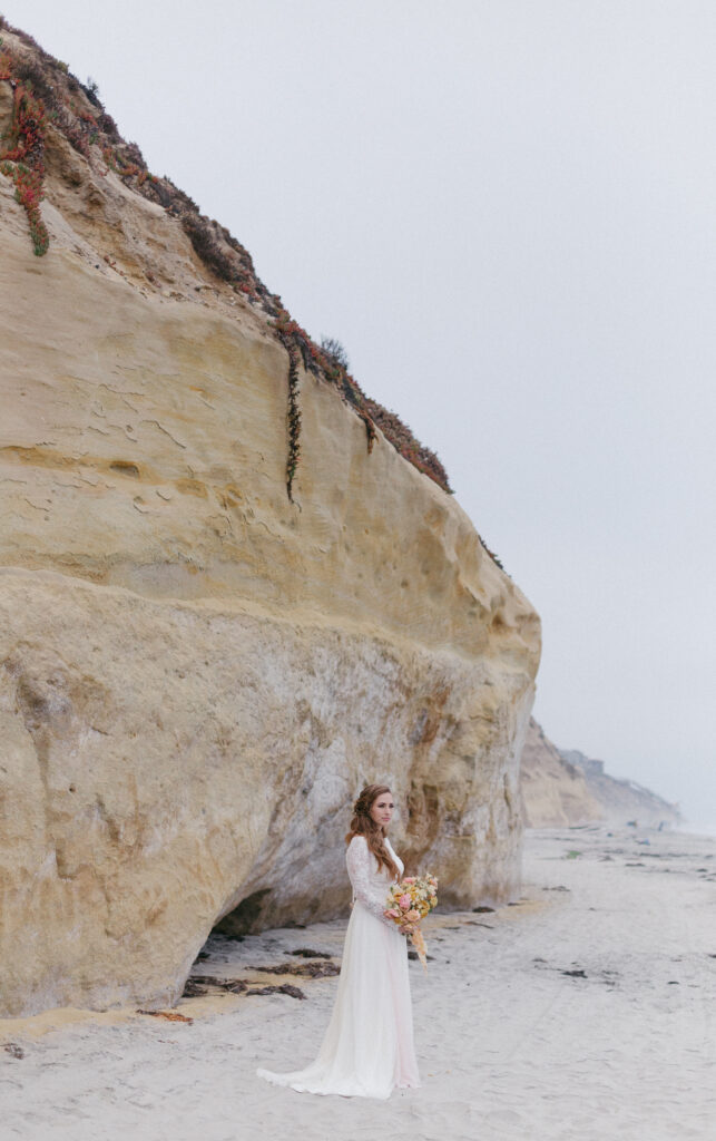 A bride poses on the beach during her small wedding in San Diego, California.