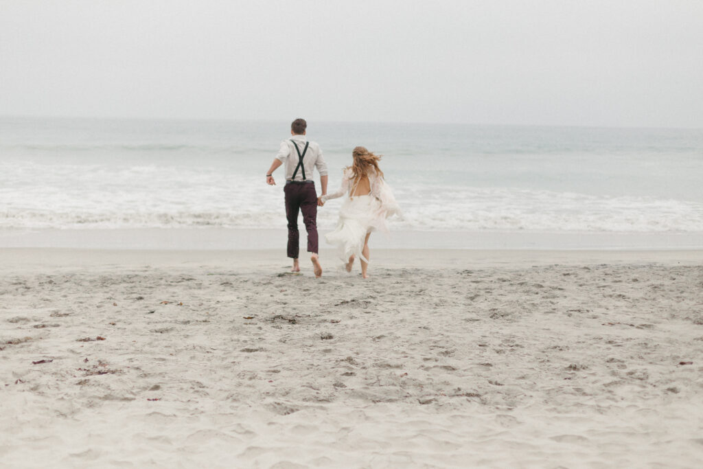 Bride and groom run away together on the beaches of San Diego.