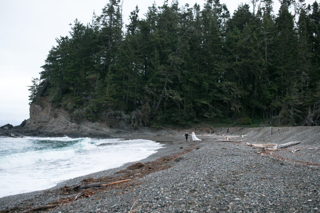 Bride and groom walk along the shore of Ahgate Beach Lodge in Port Angeles, Washington.